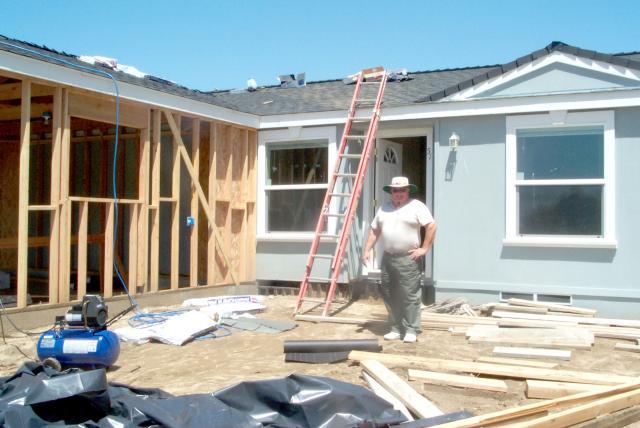 Lot51_w B Bert Caster, Developer of Oak Tree Ranch posing in front of a work in progress. In this development, each manufactured home typically has an attached garage with its roof line matching that of the home.